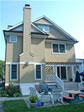 Rear elevation of custom modular home featuring a fireplace and Pergala-covered deck